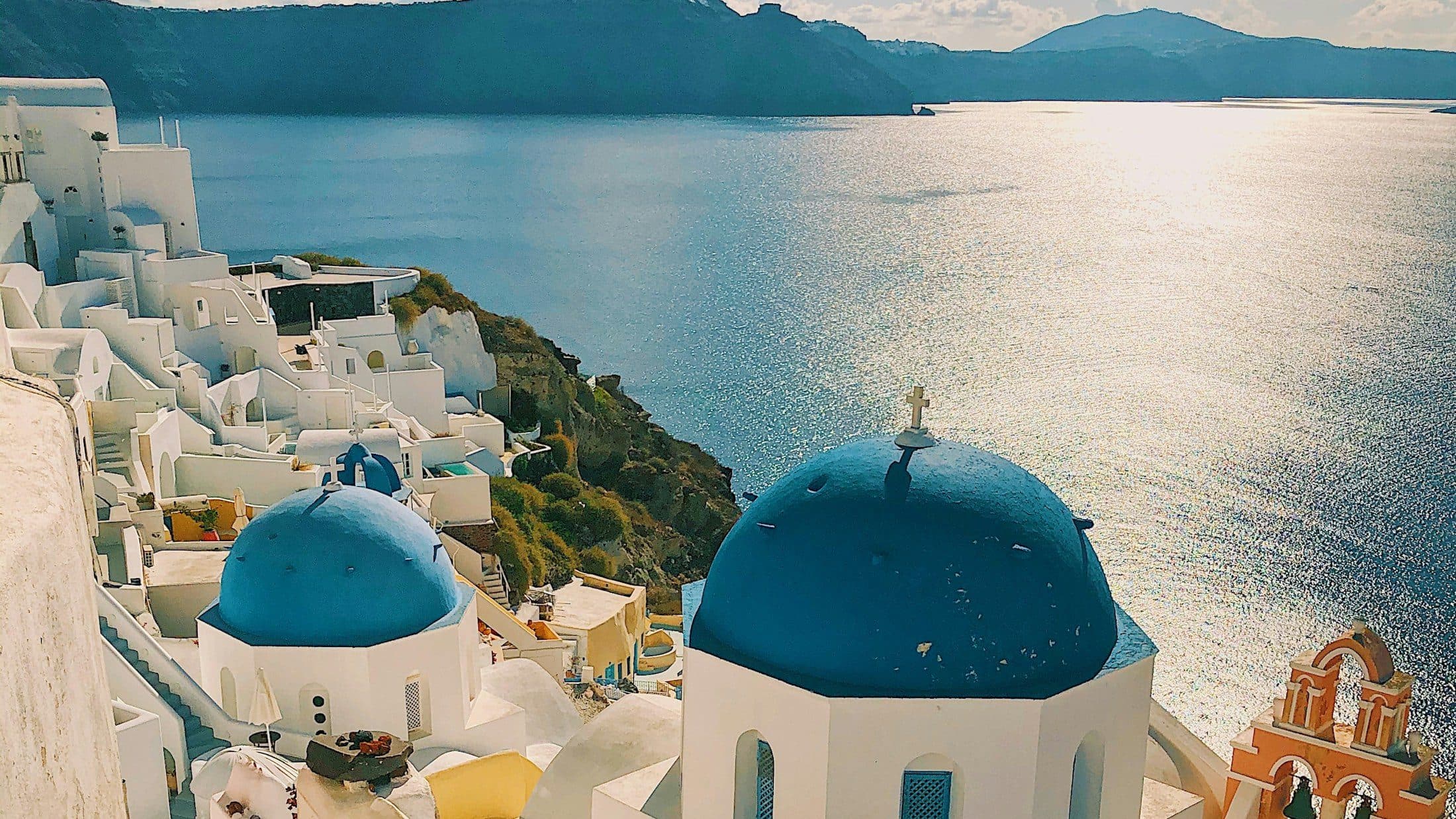 Blue church domes and white houses above the sea in Oia, Santorini.